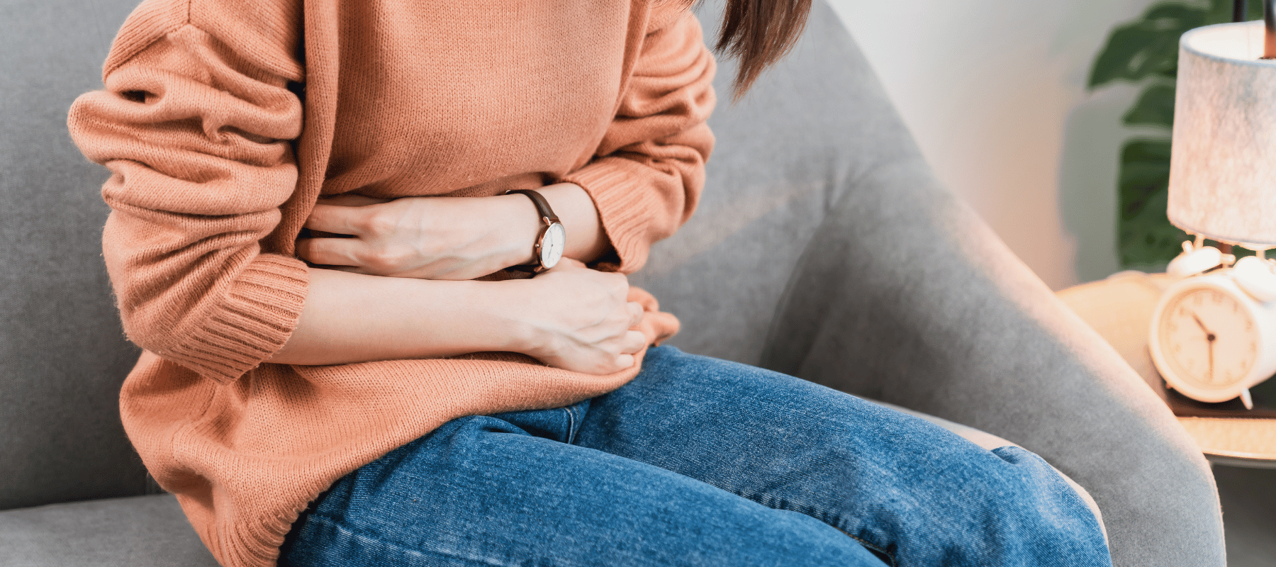 Frau mit Leaky Gut Syndrom die Schmerzen im Bauch hat und sich am Bauch festhält